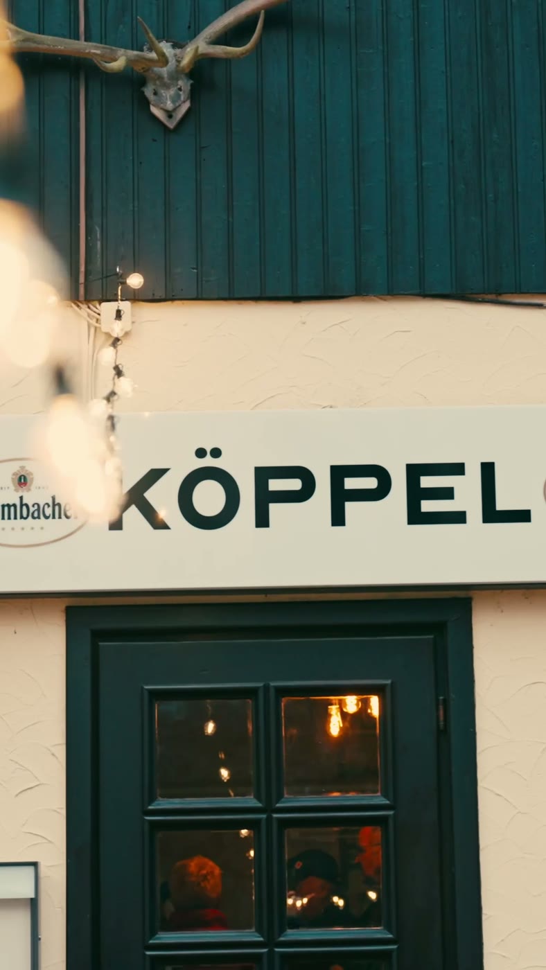 Beleuchtete Fassade der Gaststätte Der Köppel mit Geweih und Lichterketten in der Abenddämmerung